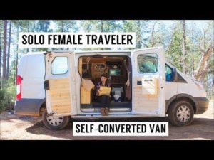 An image of a woman sitting at a computer in her van home, with the title "Solo Female Traveller, Self-Converted Van"